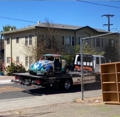 T202 at Oakland Tech picture of old VW bug loaded on a tow vehicle and headed for the scrap yard